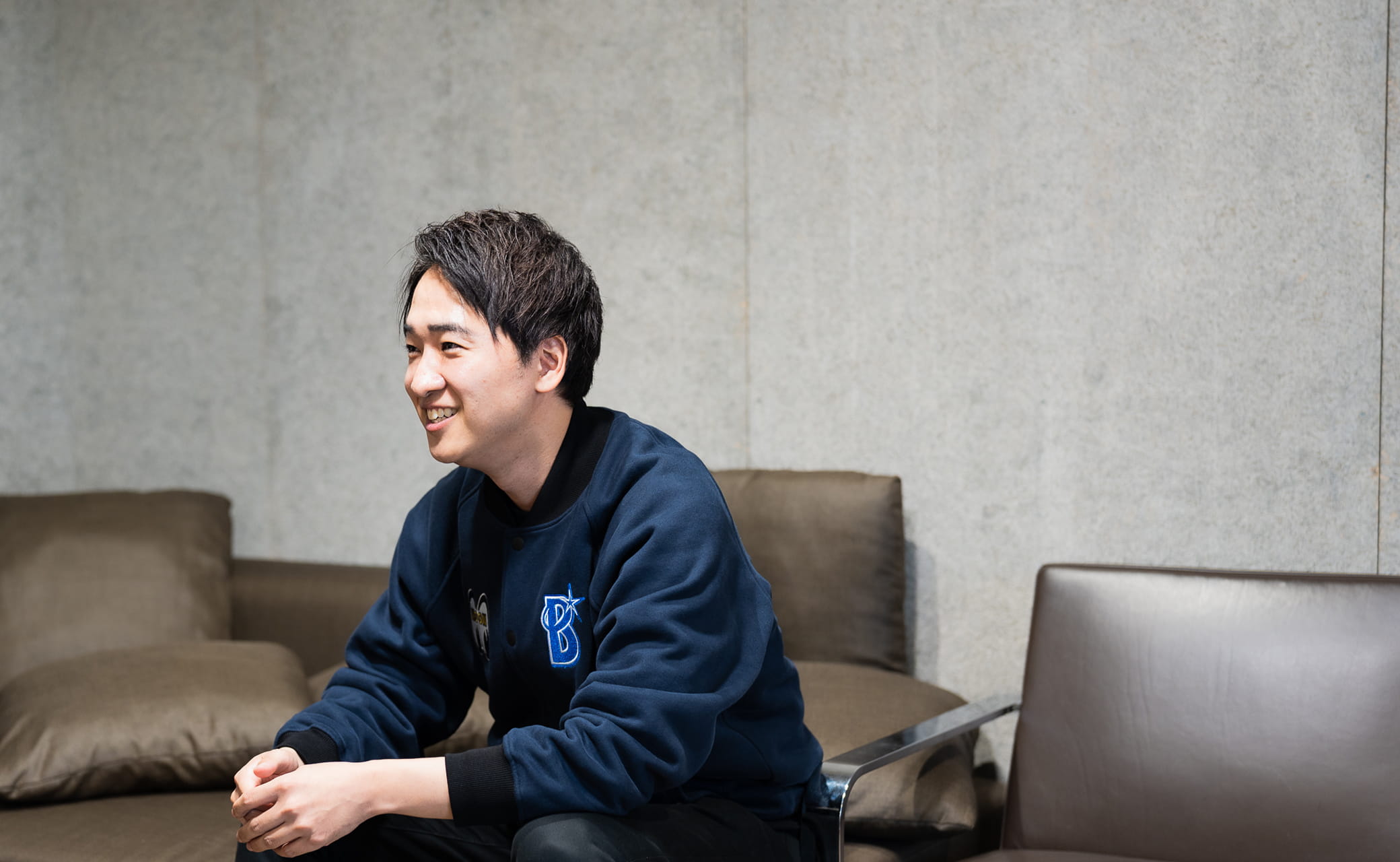 座って左を向いてインタビューを受ける男性