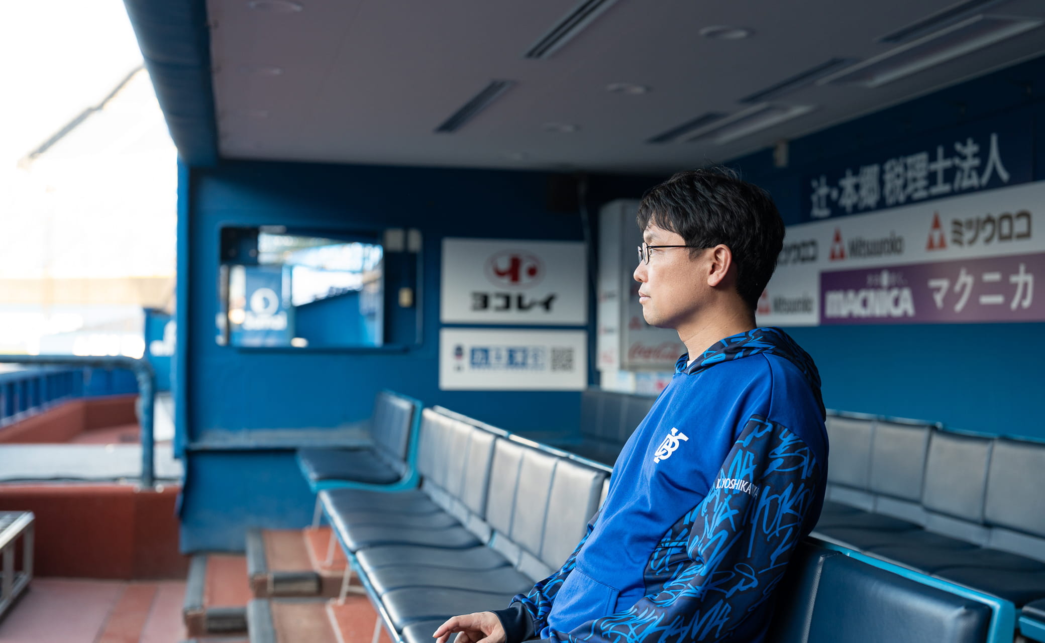 ベンチからグラウンドを見つめる男性